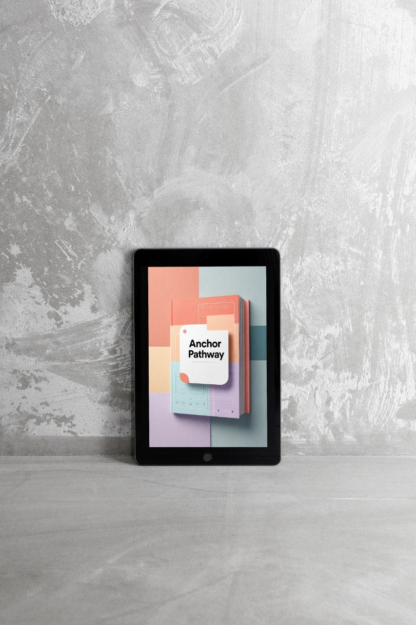 A tablet device standing upright on a light gray surface against a textured gray wall, displaying a colorful cover design with the text 'Anchor Pathway'.