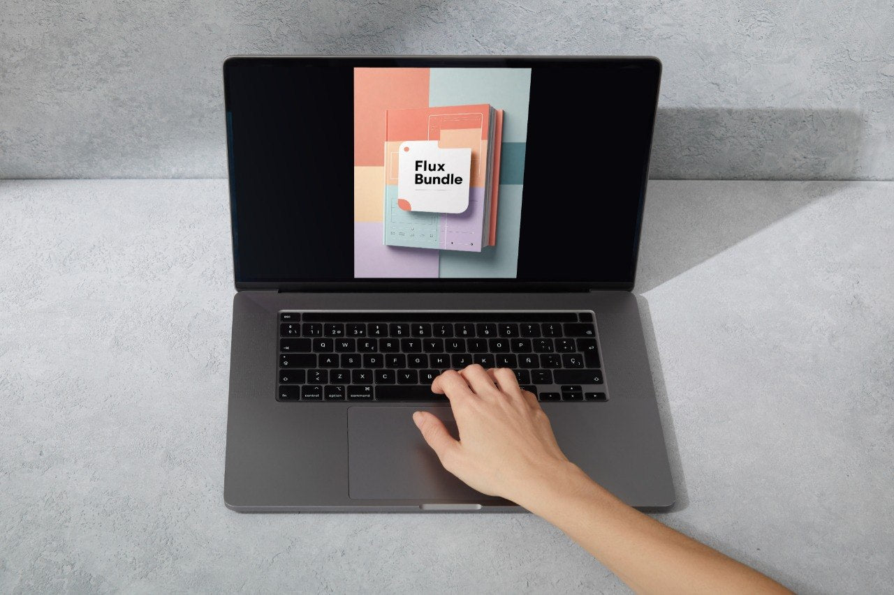 A gray laptop on a light gray surface with a hand resting on the trackpad. The screen displays a colorful graphic with the text 'Flux Bundle'.